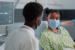 close-up-physician-talking-young-patient-bed-wearing-face-masks-man-working-as-specialist-discussing-healthcare-treatment-medicine-with-sick-woman-during-coronavirus-pandemic-min